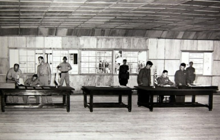 1953.7. 남측의 해리슨 중장과 북측의 남일 대장이 협정문에 서명하고 있다. 이 서명 장소가 위 사진 속에 새로 지어진 목조 건물이다.
