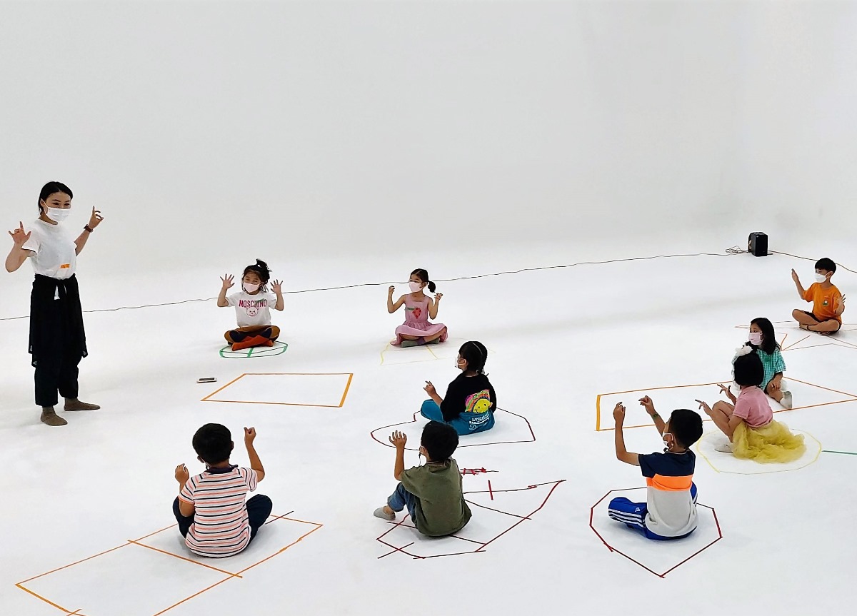 자기만의 영역에 앉아 댄스강사의 동작에 따라 하는 아이들